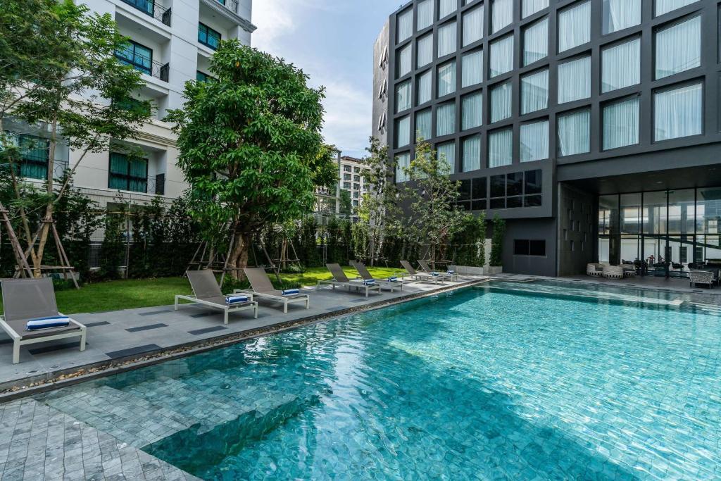 uma piscina com espreguiçadeiras e um edifício em Best Western Plus Nexen Pattaya em Pattaya Central