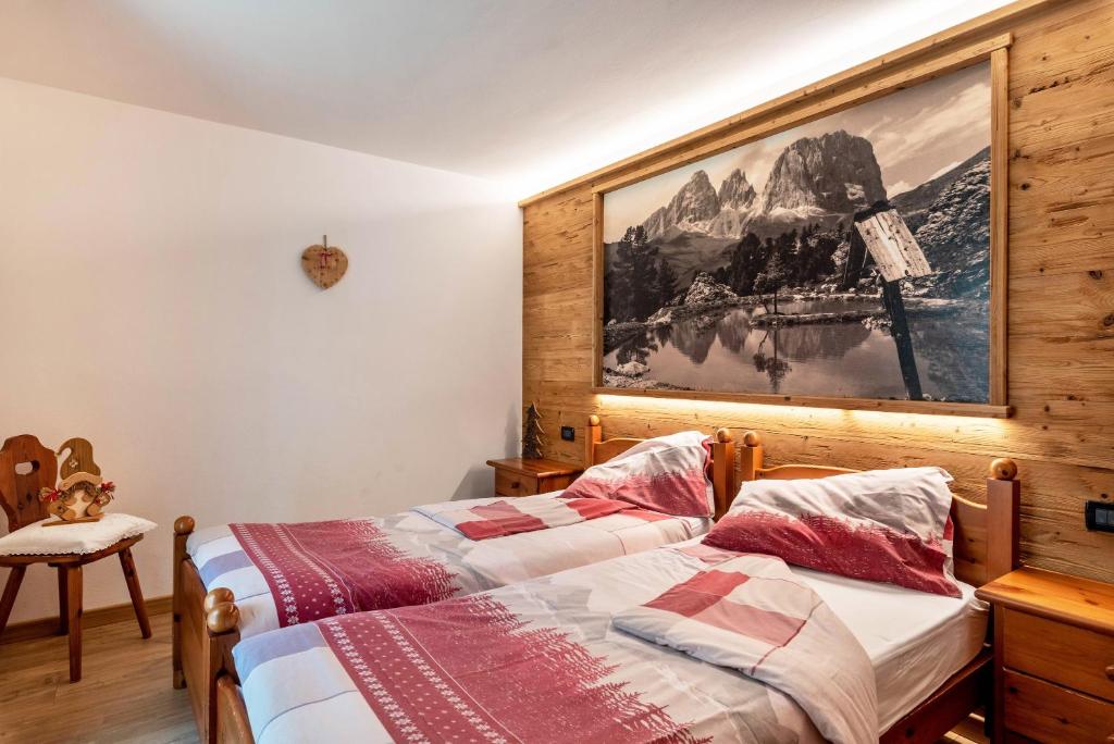 a bedroom with two beds and a picture on the wall at Betites Trilocale in Canazei