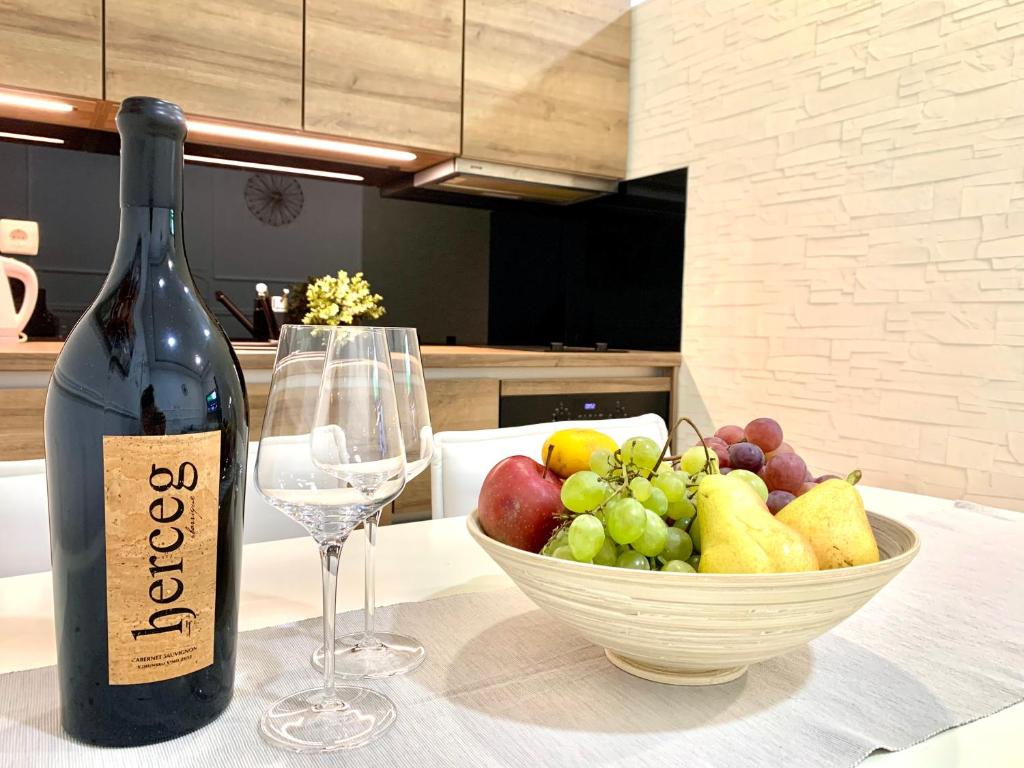 a bottle of wine and a bowl of fruit on a table at Croatia_Zagreb Apartment in Zagreb