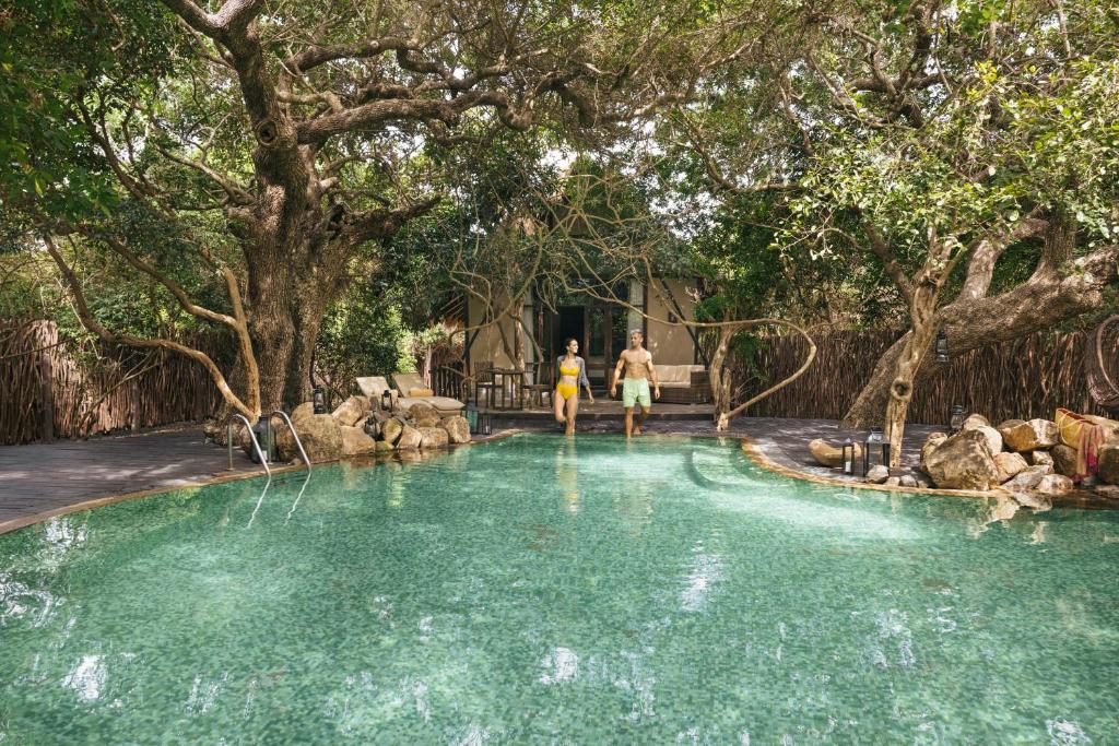 two people walking in a pool of water with trees at Uga Jungle Beach in Trincomalee