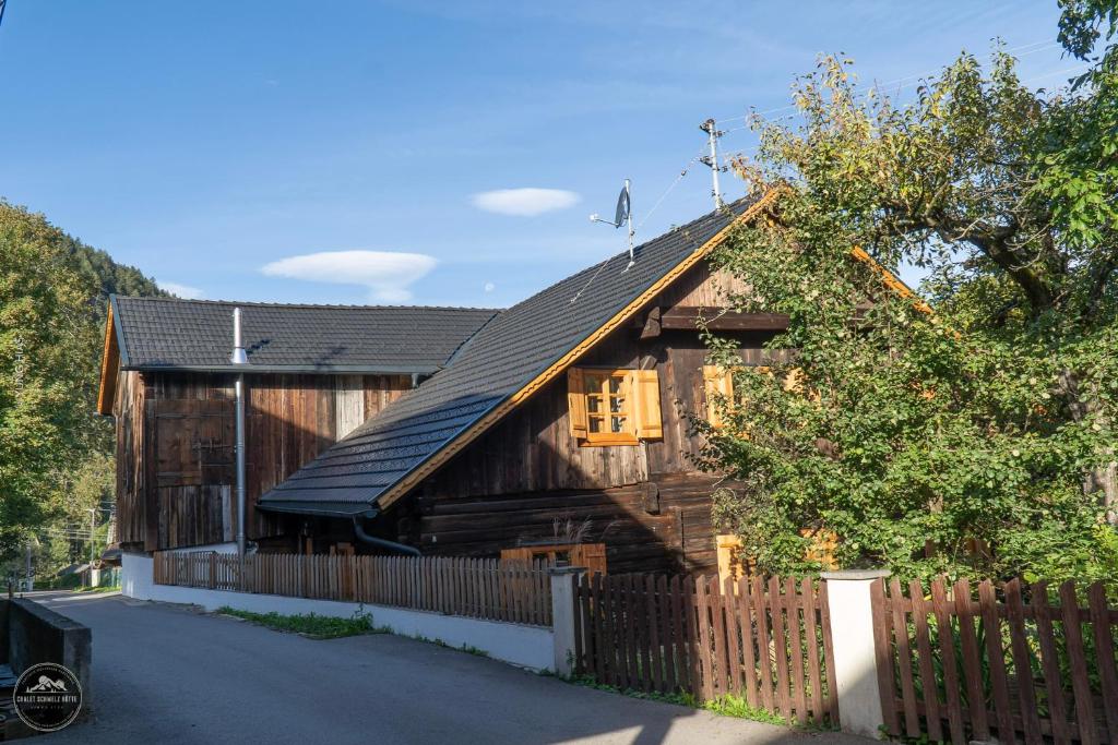 uma casa de madeira com uma cerca em frente em Chalet Schmelz Huette mit Sauna und Garten em Flattach