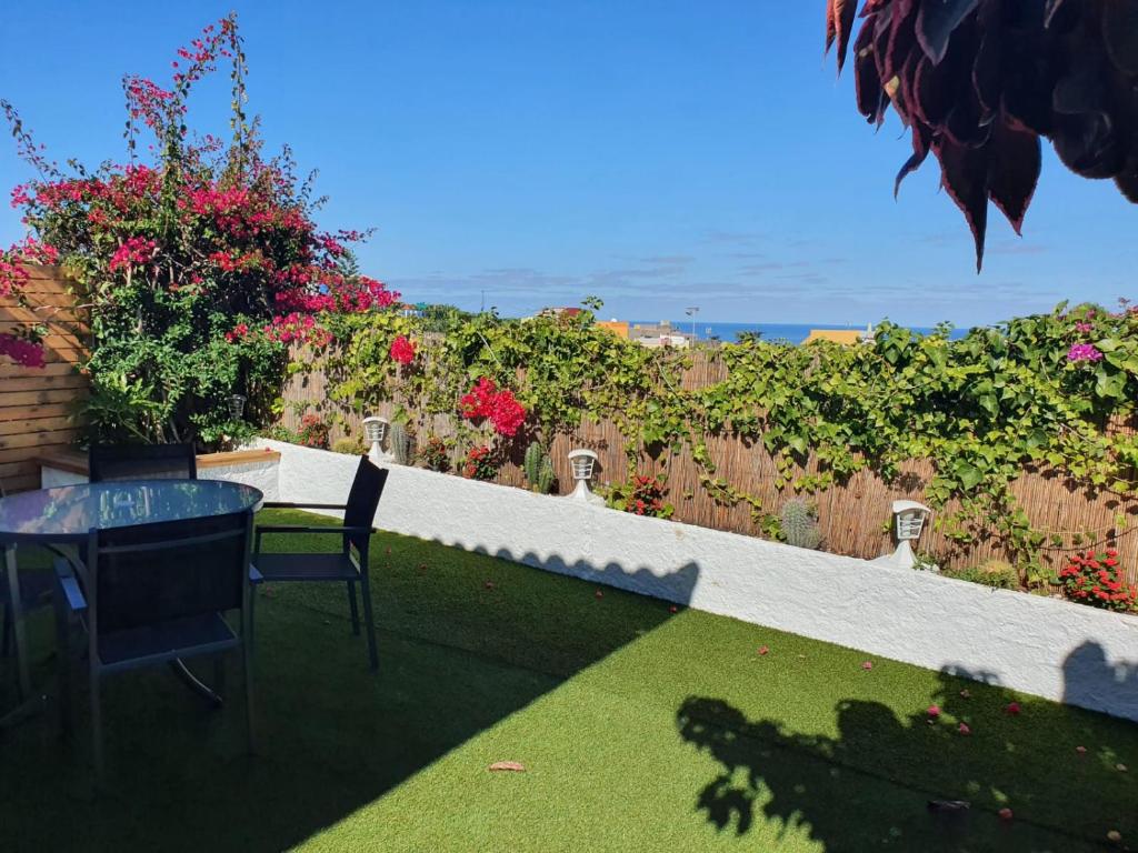 un patio con mesa, sillas y flores en Cozy and intimate bungalow in Puerto de la Cruz, en Puerto de la Cruz