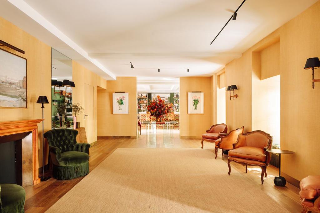 A bright hotel sitting room with a fireplace and upholstered seating.