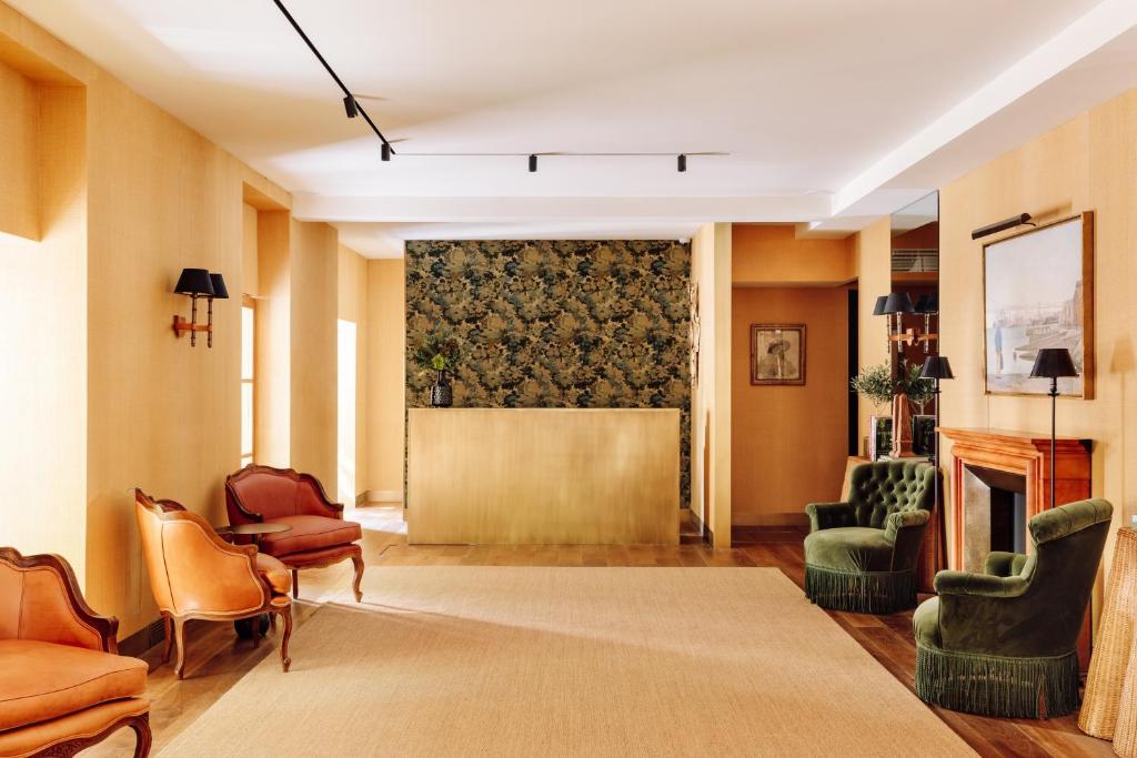 A broad hotel sitting room with varied lounge chairs, a patterned wall panel and a fireplace area.