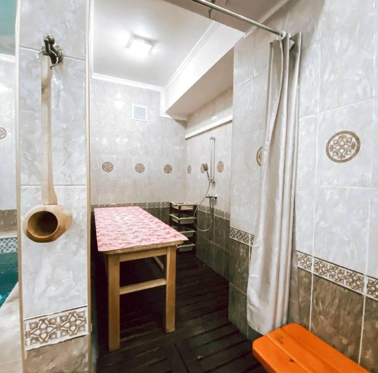 baño con ducha y mesa. en Galeon Hotel en Bishkek
