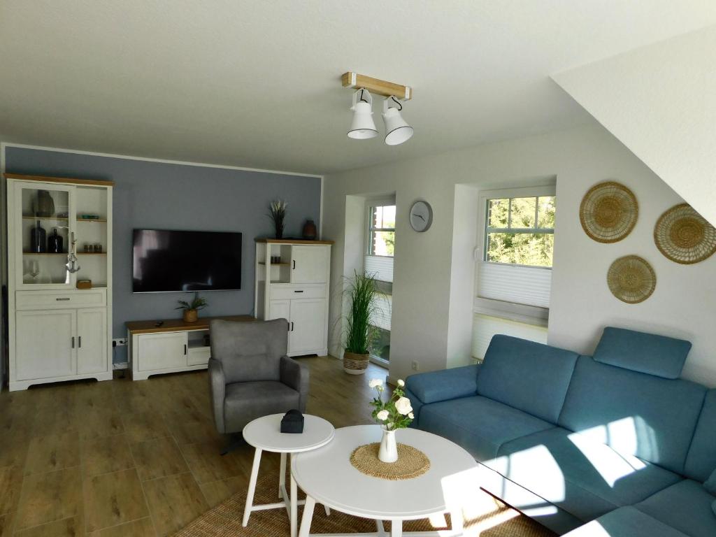 a living room with a blue couch and a table at Grachtensteern in Greetsiel