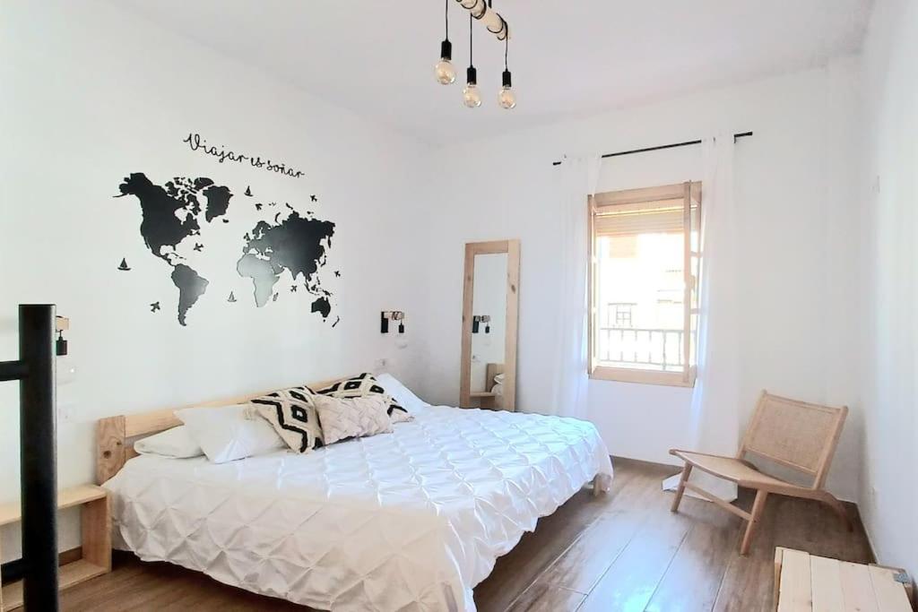 um quarto com uma cama e um mapa do mundo na parede em Limerencia: tu hogar en este blanco pueblo em Frigiliana