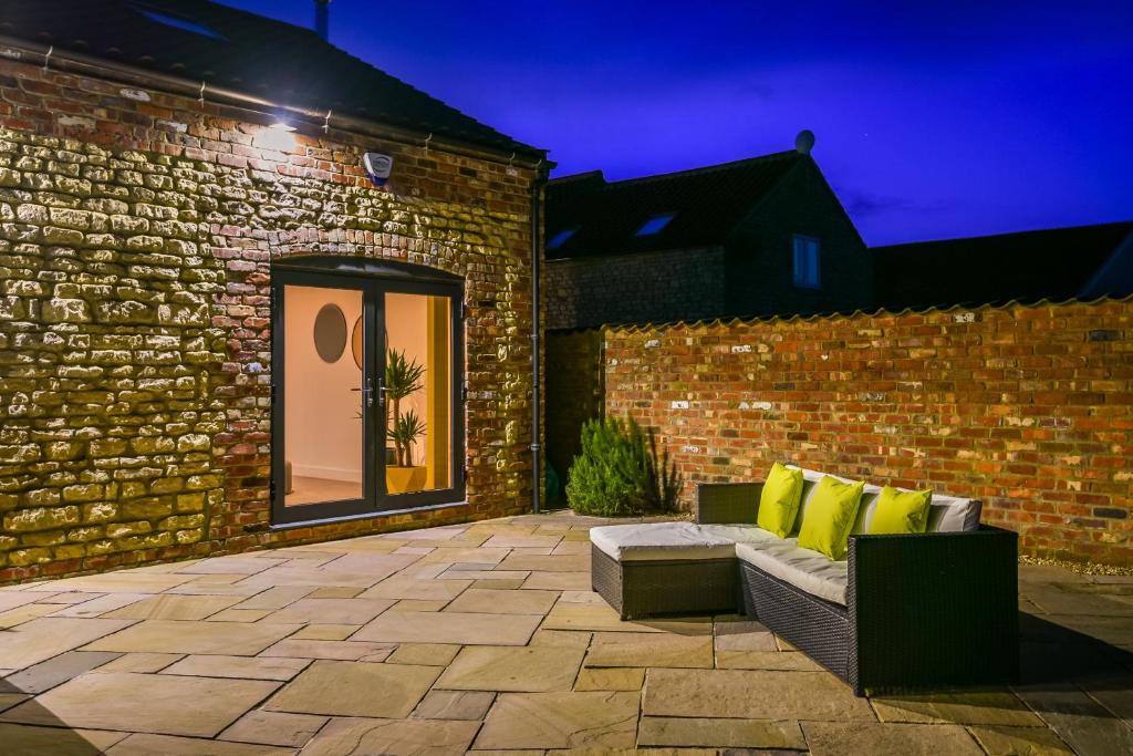 a patio with a couch and a brick wall at Immaculate 4-Bed Cottage in Lincoln in Sudbrooke