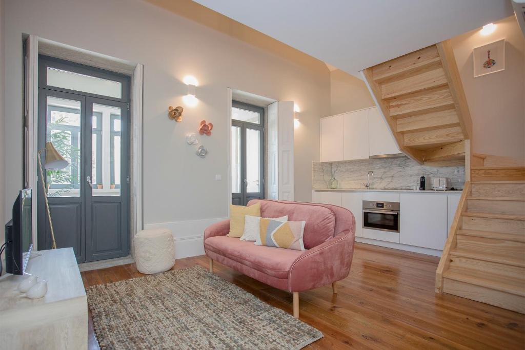 un soggiorno con una sedia rosa e una scala di Liiiving in Porto - Santa Catarina Twin Apartments a Porto