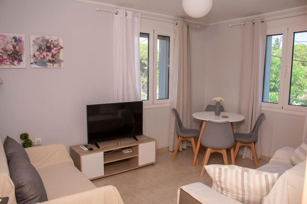 a living room with a couch and a tv and a table at Anadora 2: Hospitable stone house with yard in Alexandroupoli