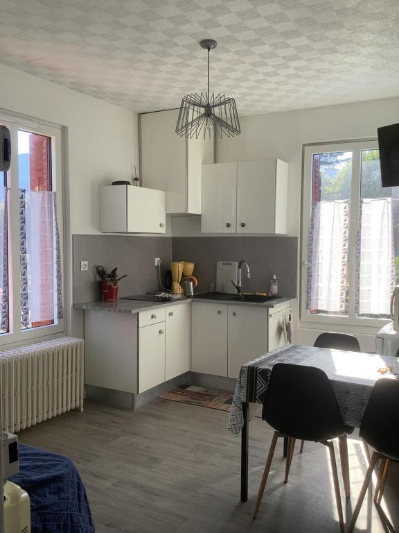 een keuken met witte kasten en een tafel met stoelen bij T2 proche du lac in Aix-les-Bains