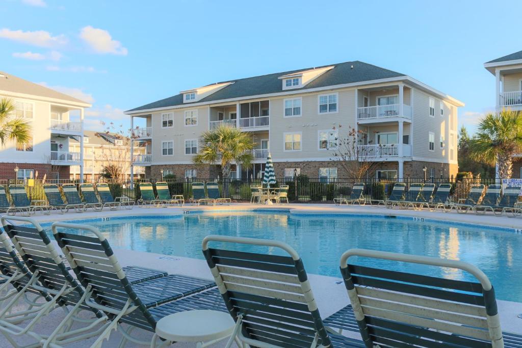 a large swimming pool with chairs and a building at River Oaks Golf Resort in Myrtle Beach