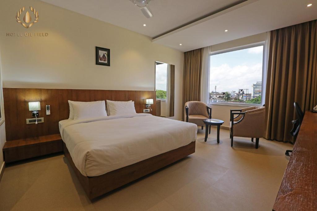 ein Hotelzimmer mit einem großen Bett und einem Fenster in der Unterkunft Hotel Oil Field in Duliāgaon
