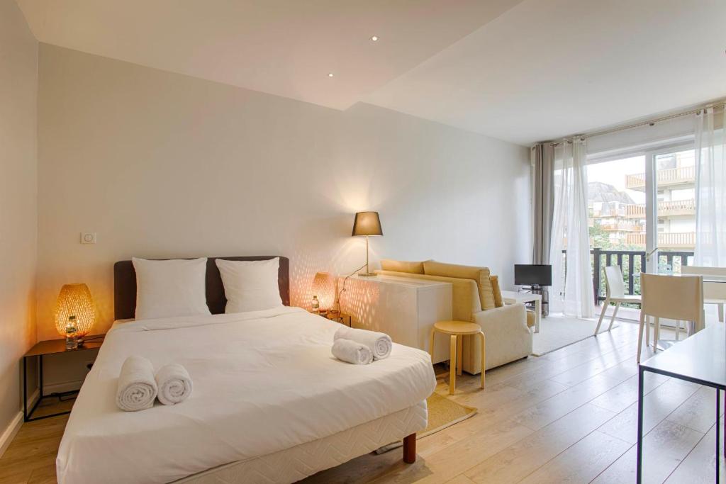 a bedroom with a large white bed and a living room at La Villa Normande - Studio - Deauville Centre in Deauville