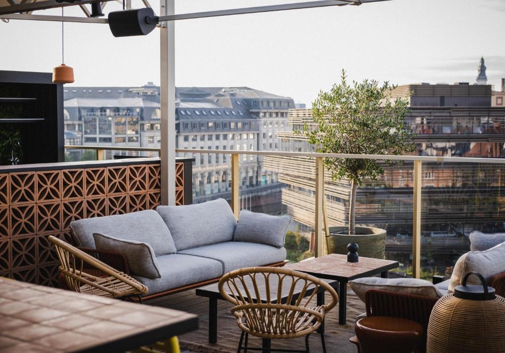 een balkon met een bank, stoelen en tafels bij Yalo Urban Boutique Hotel Gent in Gent