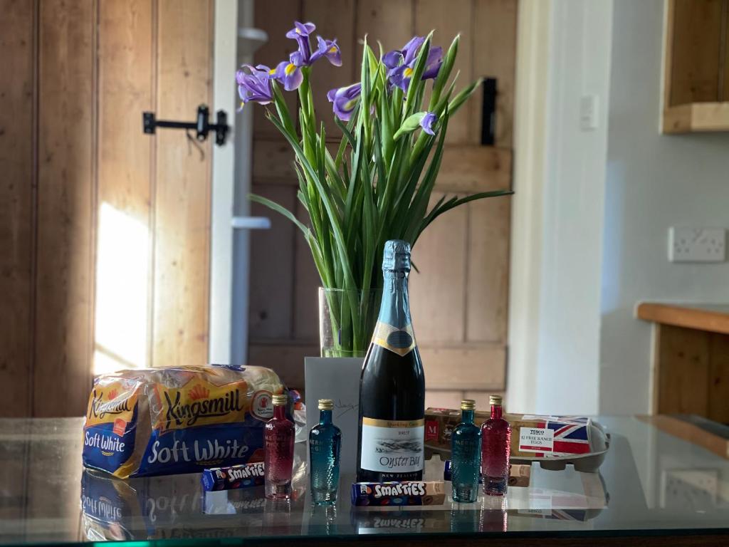 a bottle of wine sitting on a counter with a vase of flowers at Beautiful Character Thatched Pet Friendly House in Enford