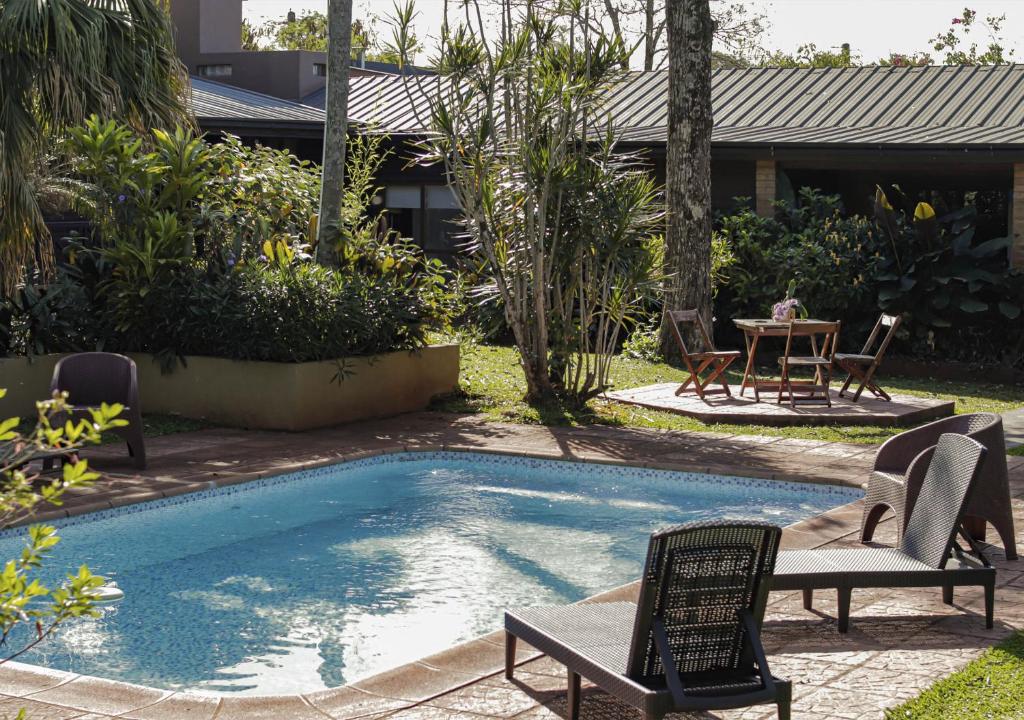 una piscina con due sedie a sdraio e un tavolo di El Descanso Iguazú by DOT Cabana a Puerto Iguazú