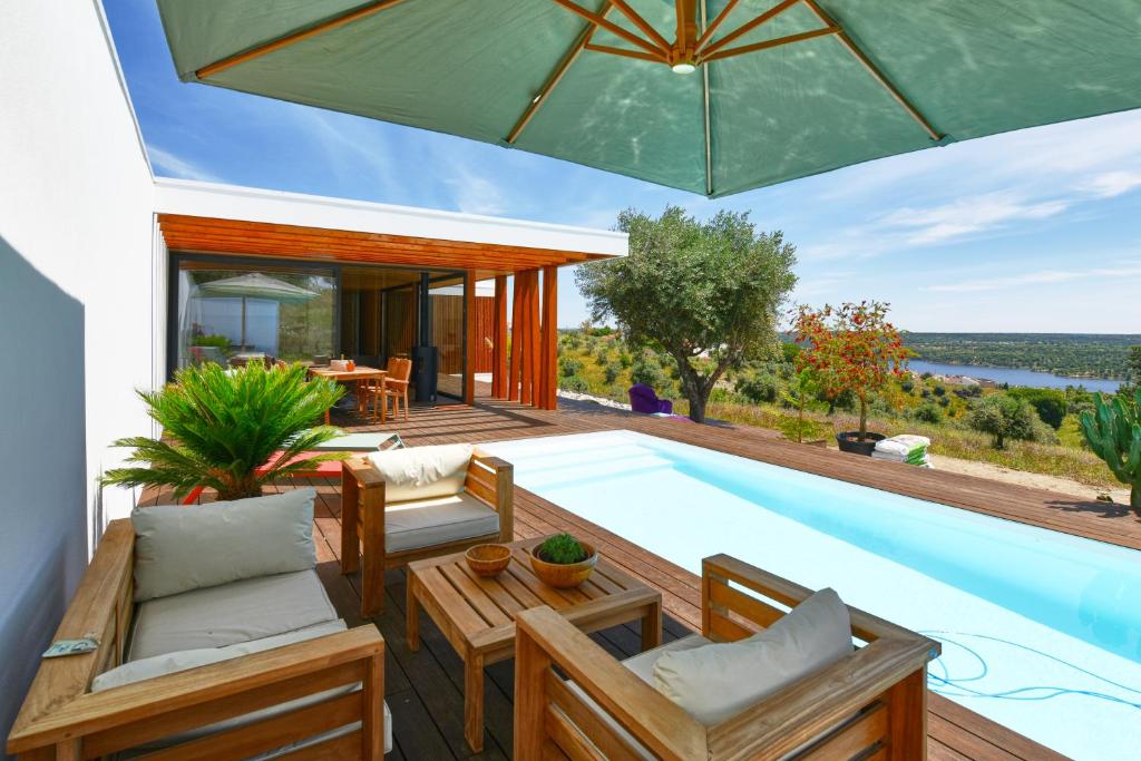 a patio with a pool and chairs and an umbrella at Casa Chão de Ourém, O charme em Montargil. in Montargil