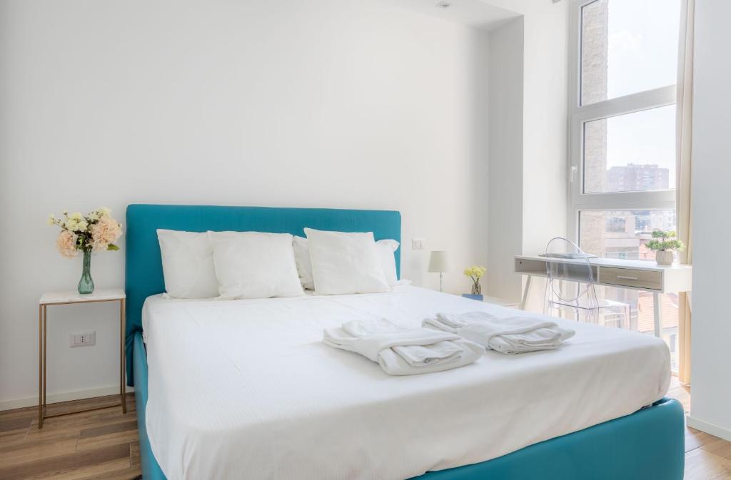 a bedroom with a blue and white bed with towels on it at Sunlit 1 Bedroom Apt in Porta Nuova in Milan