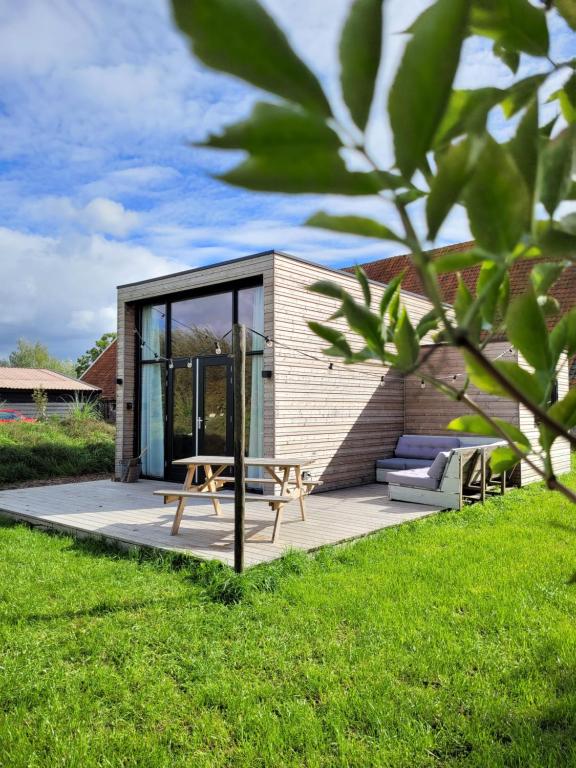 a small house with a picnic table and a bench at NEW! Tiny House Lantliv Oostkapelle, bij de boer in Oostkapelle