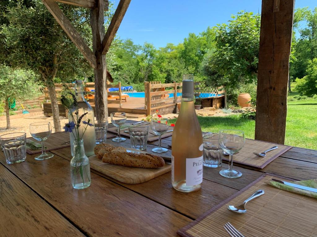 a bottle of wine sitting on a wooden table with glasses at Gites de Verger, stylish self catering cottages in Sos in Sos