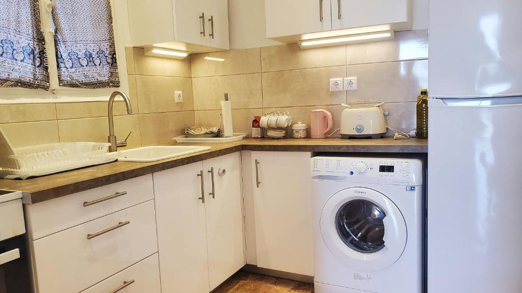 uma cozinha com uma máquina de lavar roupa e um lavatório em Armenian Huts - Beach Apartments em Vári