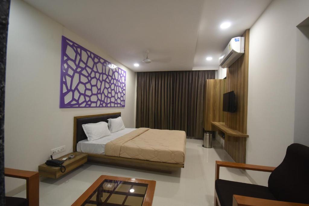 a bedroom with a bed and a couch and a table at The Pacific Hotel in Vadodara
