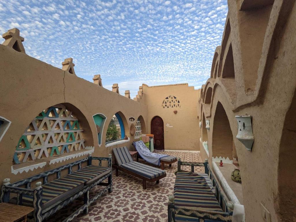 un patio avec des bancs et des chaises dans un bâtiment dans l'établissement Scorpion House Luxor, à Louxor