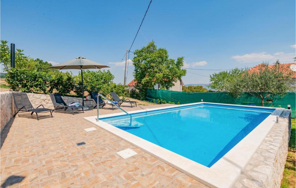 - une piscine avec 2 chaises et un parasol dans l'établissement Cozy Home In Runovic With Outdoor Swimming Pool, à Runović