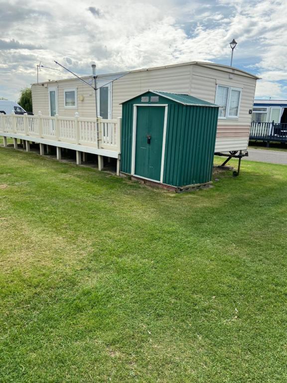 uma casa com uma porta verde num campo de relva em i13 the chase caravan park em Ingoldmells