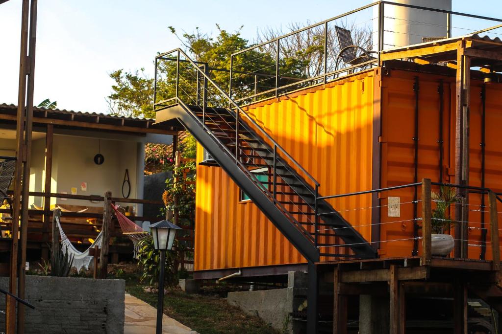 una casa naranja con una escalera delante de ella en João de Barro camping e suítes, en Alto Paraíso de Goiás
