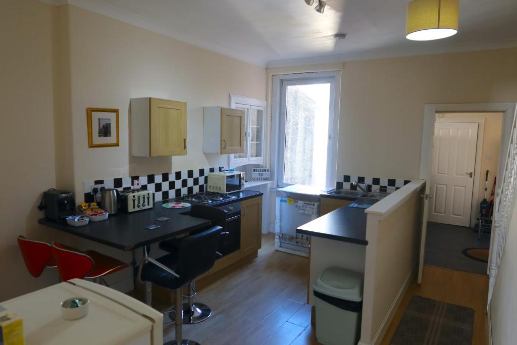 a kitchen with black counters and a table in it at Large Apartment near the Beach & World Class Golf in Methil