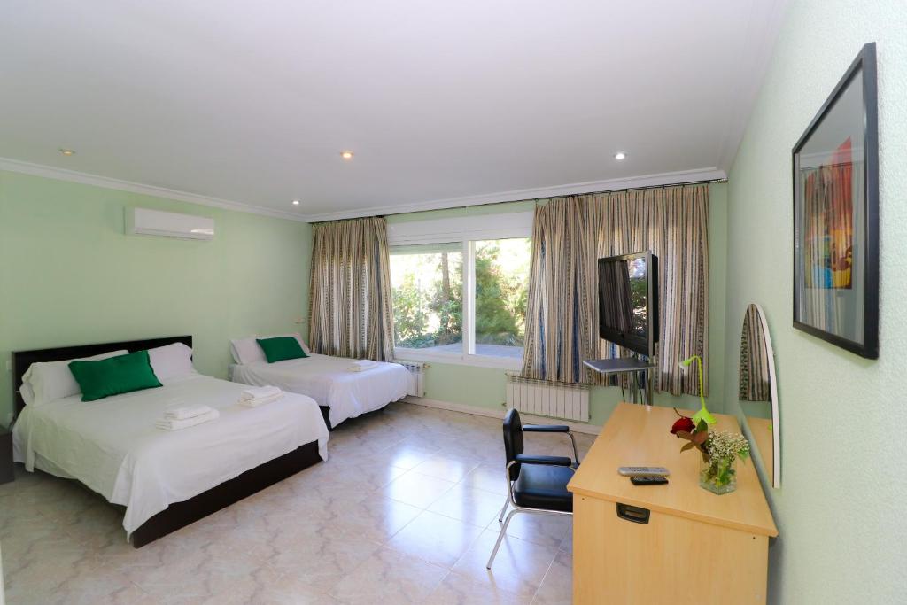 a hotel room with two beds and a desk at Casa Rural El Retiro de Gredos by RetiroRural in Arenas de San Pedro