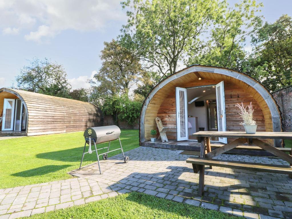 een rond huis met een grill en een tafel bij Larch in Uttoxeter