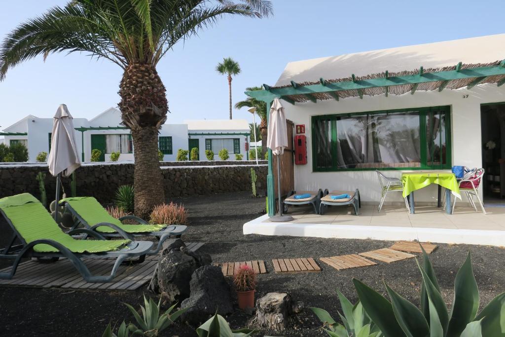 a patio with chairs and a house with a palm tree at Golondrina 17 - Bungalow con giardino a Matagorda - Fronte mare - Aria condizionata - Piscina in Los Pocillos