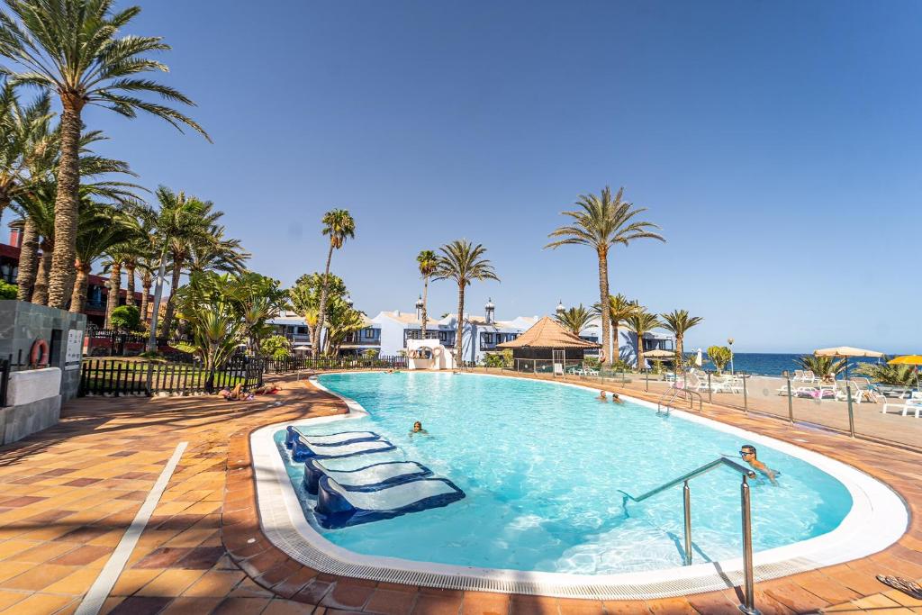 una piscina en un complejo con palmeras y el océano en Casa Martín., en Playa del Águila