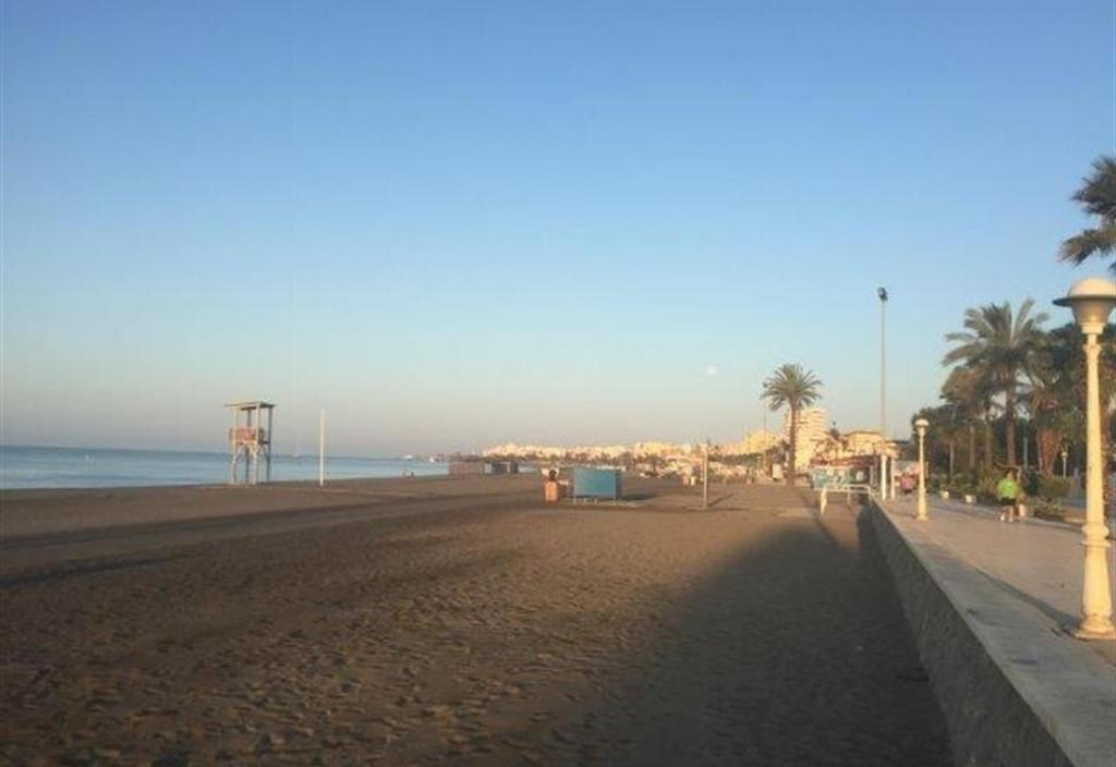 una playa de arena con palmeras y el océano en Sea front house, en Torre del Mar