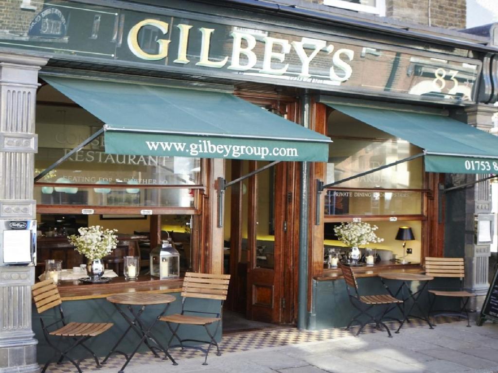 um restaurante com mesas e cadeiras em frente em Gilbey's Bar, Restaurant & Townhouse em Windsor