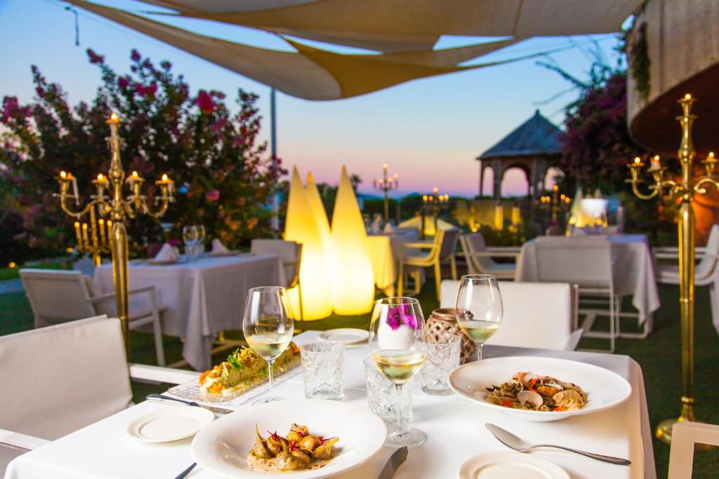 una mesa con platos de comida y copas de vino en Augusta Eco Wellness Resort 4 Superior, en Sanxenxo