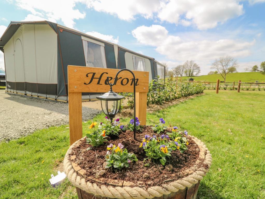 a sign in a flower bed in front of a rv at The Heron in Rhayader