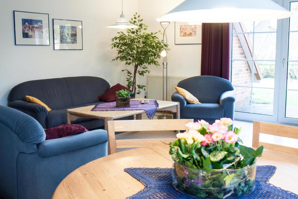 een woonkamer met banken en een tafel met bloemen bij Haus Tjalk Ferienhaus Tjalk rechts in Norddeich