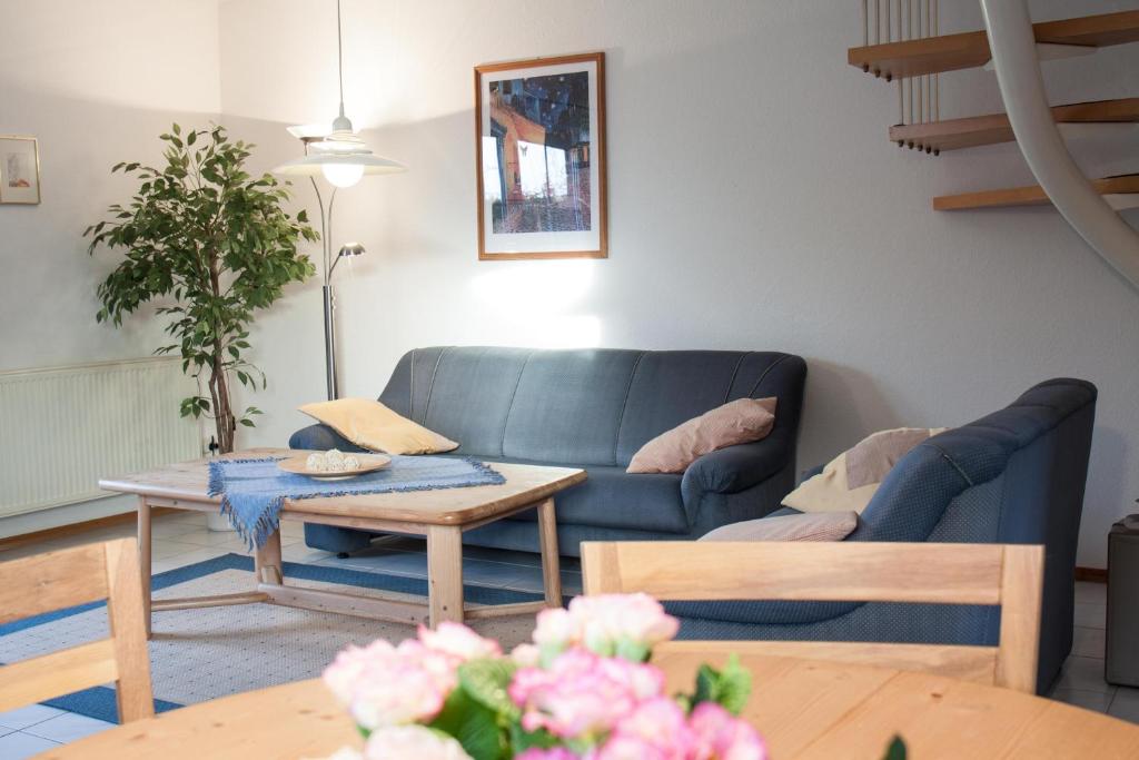 Haus Tjalk Ferienhaus Tjalk links في نورديش: غرفة معيشة مع أريكة زرقاء وطاولة