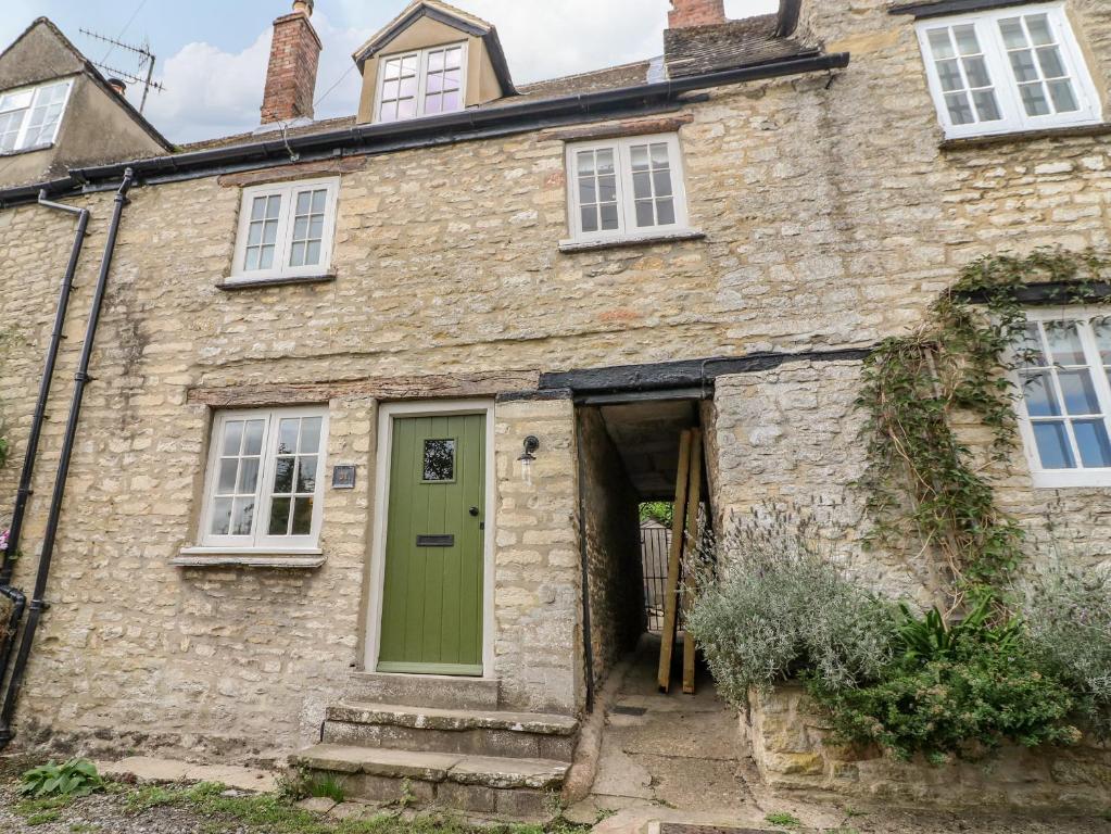 an old stone house with a green door at 31 Manor Road in Charlbury