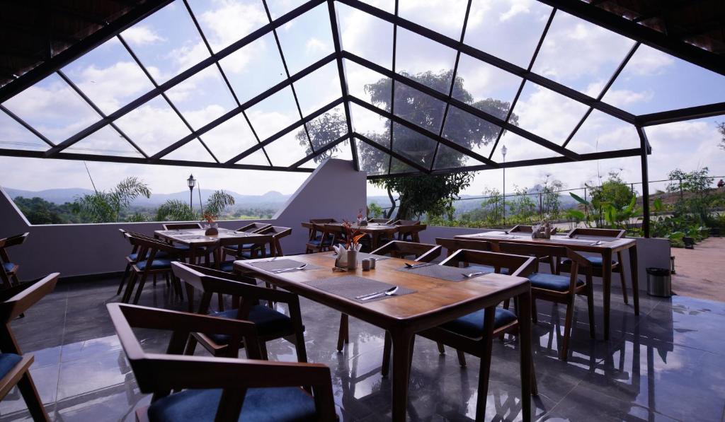 a restaurant with tables and chairs and a large window at Ravishing Retreat Resort in Rāmanagaram
