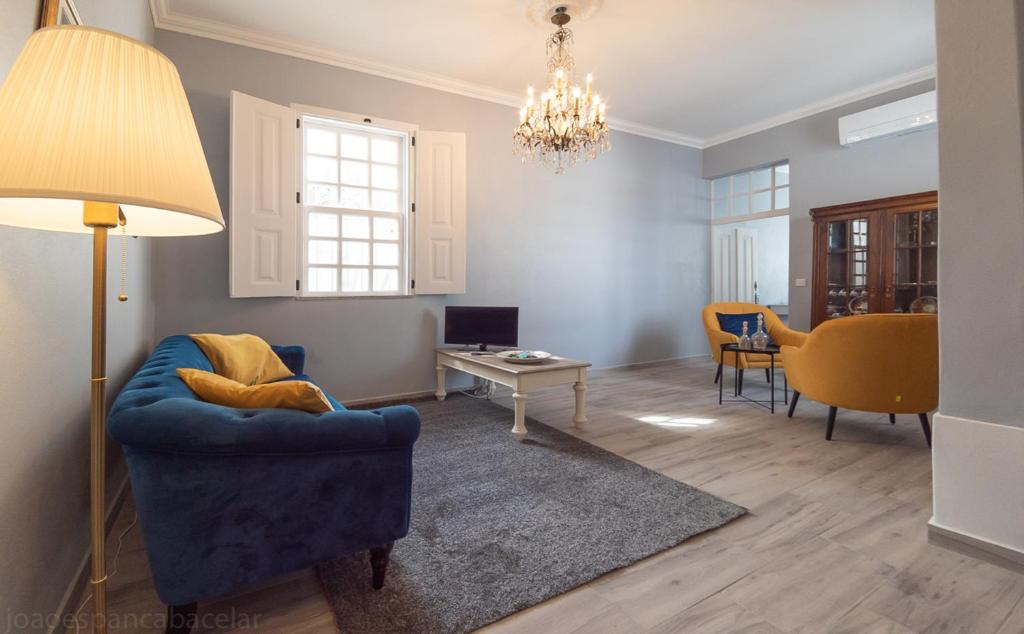 a living room with a blue chair and a table at Páteo dos Oliveira - Casa dos Senhores in Évora