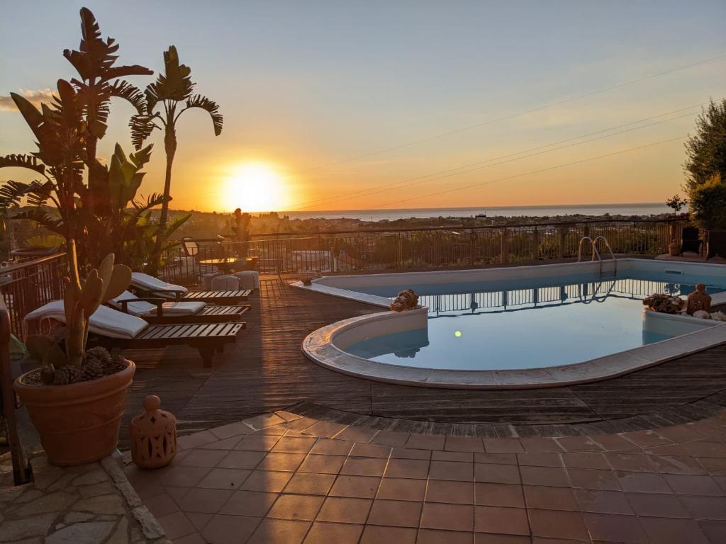 een zwembad op een patio met een zonsondergang op de achtergrond bij Villa Carly Taormina apartment with private pool in Trappitello