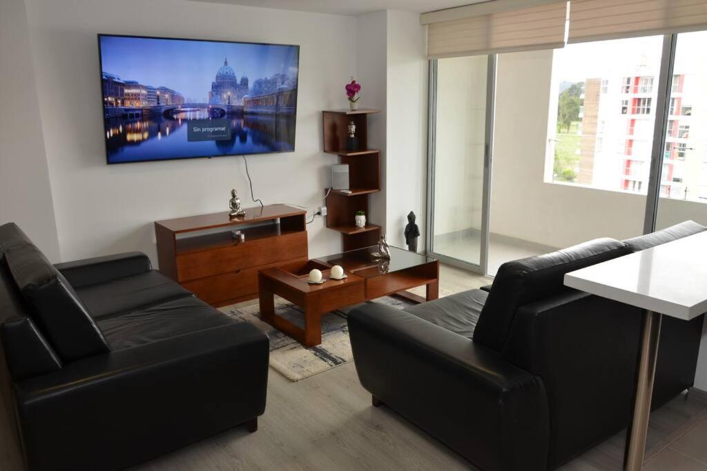 Una sala de estar con un sofá y un televisor en la pared. en Hermoso apartamento en Paipa con vista al lago Sochagota., en Paipa