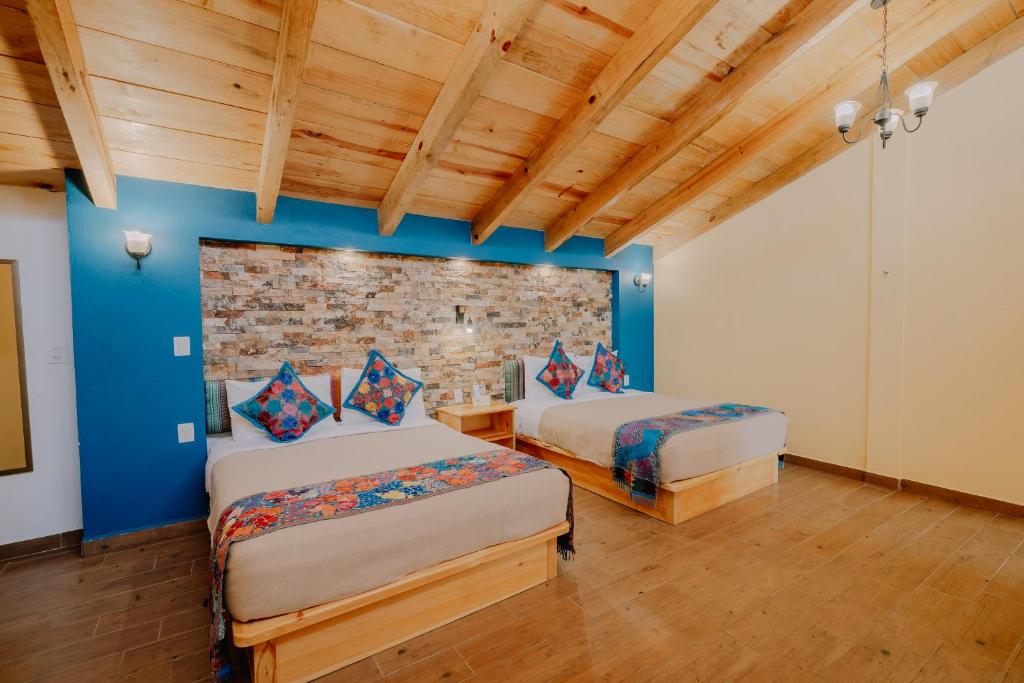 a bedroom with two beds and a brick wall at Hotel Cielo y Selva, San Cristobal de las Casas in San Cristóbal de Las Casas
