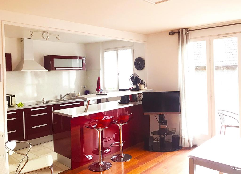 una cocina con encimera y taburetes rojos. en Appartement en plein cœur d'Aix-les-Bains en Aix-les-Bains