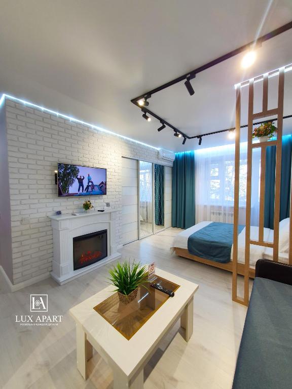 a living room with a bed and a fireplace at Lux апартаменты в центре Караганды на 45 квартале in Karagandy